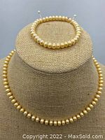 Freshwater pearl necklace and stretch bracelet displayed on a fabric jewelry stand, showing pearl texture and arrangement.