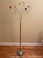 Full view of lamp with stainless steel post, round base, seven spiral arms with glass shades, lamp off