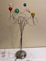 Full view of lamp showing chrome round base and spiraling arms with six colored glass shades