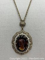 Close-up of the ornate gold tone cameo pendant with surrounding pearl beads