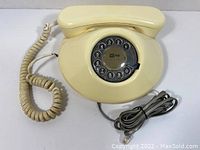 Front view of cream rotary phone showing dial and handset with coiled cord