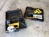 Wide view of Dewalt cordless circular trim saw with battery in case, Dewalt reciprocal saw with extra blades in separate case on floor.