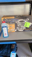 Photo of the Calphalon Collector's Edition fondue set boxed with the original packaging shown alongside a bottle of Isopropyl Alcohol for scale or safety.