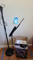 Full view showing black microphone stand with mic, black adjustable music stand, and boxed ION House Party speaker system with manual on top.