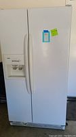 Full view of a white Kenmore side by side refrigerator showing the exterior doors and handles.