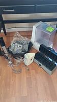 Kitchen appliances on wooden floor: sous vide immersion circulator with lid, electric hand mixer, immersion blender, waffle iron, Crockpot insert.