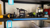 Shelf with several power tools including drill, sander, work light, and Makita tool