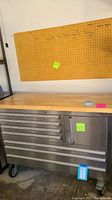 Front view of tool chest with wood top and pegboard mounted on wall above