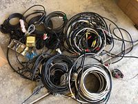 A large mix of various coaxial, A/V cables, wires, and splitters laid out on the floor with visible labels and connectors.