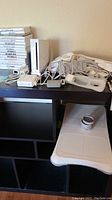Photo of entire lot showing Wii console, balance board, stacked Wii game cases, and various cables and controllers.