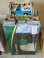 Photo showing boxed John Deere radio-controlled tractor along with boxed blue Step Siders toy truck.