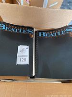 Two Complete Beatles Song Album books inside a cardboard box showing their black covers with blue and orange lettering, one with comb binding and the other paperback or staple bound.