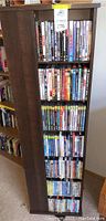 Photo of a wooden storage shelf holding many DVDs organized vertically across five shelves. Various DVD titles are visible.