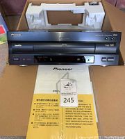 Front view of player showing LaserDisc and DVD logos, foam inserts and manuals