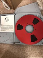 Reel to reel tape with red tape in gray plastic case, includes dBaseIV software manual part