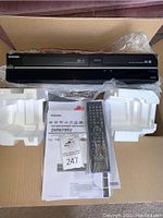 Front view of DVR670KU main unit with remote and manual in Styrofoam packaging