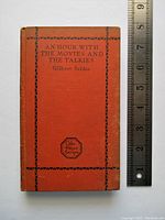 Front cover shows the book title, author, and decorative border on orange hardcover alongside a ruler for scale.