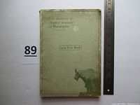 Front cover of the softback book titled 'The Academy of Natural Sciences of Philadelphia 1929 Year Book' with ruler for scale and visible signs of wear and corner bends.