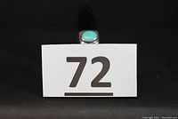 Ring displayed on a black ring stand with a number tag '72' placed in front.