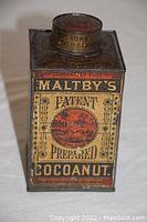 Front view of Maltby's Patent Prepared Cocoanut advertising tin showing red circular tropical illustration and text.