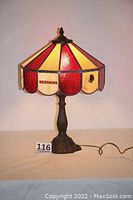 Full view of the stained glass lamp with the illuminated shade showing Redskins logo and team colors, with intricate base and power cord.