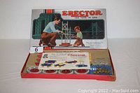 Open box view showing booklet, metal wheels, gears, and various metal pieces arranged inside the box.