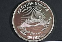 Front of the silver medal showing the Golden Gate Bridge with San Francisco skyline for its 50th anniversary.