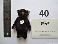 Mini brown Steiff teddy bear up to 4 inches tall sitting next to a ruler, with original tags and information card visible. Photo taken to show scale, authenticity, and condition.