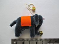 Small dark blue mohair elephant plush with orange felt saddle, plastic eyes, white tusks, pull string with bell, alongside a ruler showing about 5 inch length.