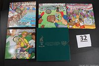 Four Young Collectors Olympic Series half dollar coins in colorful illustrated folders featuring basketball, baseball, swimming, and soccer, arranged with the outer box and lot number.