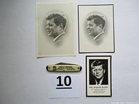All three John F. Kennedy memorial items displayed: pen knife, two memorial cards, and matching portrait photo.