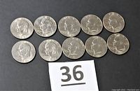 Ten 1977 Eisenhower one-dollar coins arranged in two rows on a black surface, showing the front side with Eisenhower's portrait.