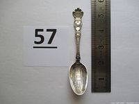 Full view of sterling silver souvenir spoon with ruler for size reference. The spoon measures approximately 5.25 inches in length.