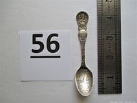 Full view of the 4-inch sterling silver souvenir spoon with ruler for size reference and lot number card.