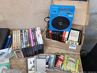 Blue North Star 8-track player with 8-track cartridges, DVDs, and CDs shown together on table surface.