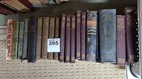 Photo showing 16 antique nonfiction and literature books arranged on a carpeted floor with visible wear on covers and spines.