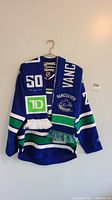 Full view of the blue Vancouver Canucks hockey jersey with two scarves draped over it.
