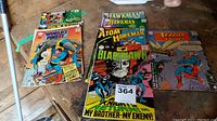 Collection of vintage comics from 1960s on floor showing covers with Superman, Hawkman, Blackhawk and Atom. Wear and tear visible.