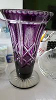 Side view of purple cut to clear glass vase showing detailed cut leaf and diamond patterns and scalloped rim.