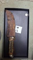 Hunting knife in leather sheath, rust visible on sheath, antler handle visible.