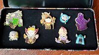 Pins arranged inside black foam in a collectible tin box showing all 8 pins in total.