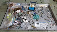 Overview tray photo showing a large assortment of jewelry items including bracelets, earrings, necklaces, tie clip, and pin
