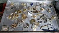 Overview of assorted jewelry including various earrings and necklaces laid out on a metal tray