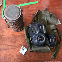 Top view showing the gas mask, carrying bag, and metal canister on a wooden surface.