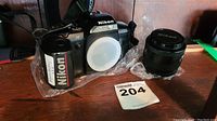 Front view showing Nikon N5005 camera body with lens mount covered and Nikon branded 35-70mm lens beside it.