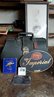 Overview of the lot showing steel sign, leather bag, cigar tin, photo frame and metal case