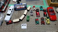 Overview of all toy vehicles and train cars included in lot on carpeted floor, showing a white Majorette limousine, several small die-cast cars, and beige train cars.