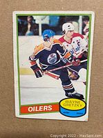 Front of the 1980-81 O-Pee-Chee Wayne Gretzky hockey card showing player in Oilers jersey and blue helmet skating on ice with colored border and text.