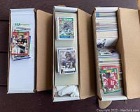 Three white storage boxes containing approximately 2,000 football cards, organized in stacks and rows within each box.