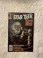 Front cover of Star Trek comic #49 showing the Enterprise and a ghostly face in a dark void with the comic title and text.